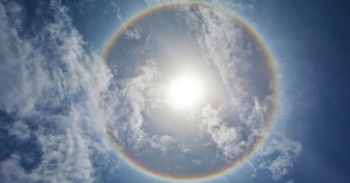 A full-circle rainbow viewed from an airplane above the clouds.